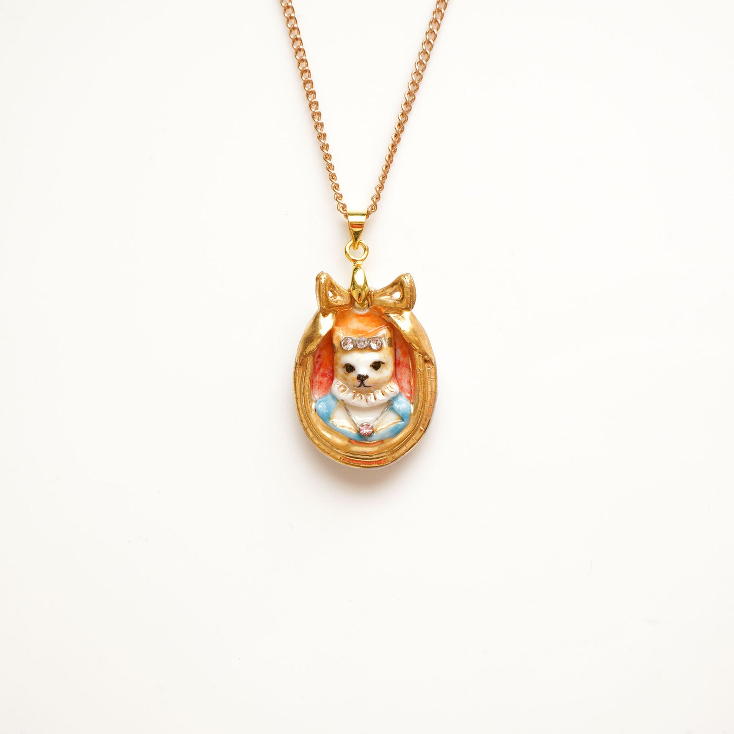 A cute Countess Naia Cat Cameo pendant in cat portrait design is a handmade porcelain and hand painted with 24ct gold, silver and colour. Embellished with Swarovski crystals for a luxurious touch. Come with 18'' gold plated necklace. Adding a chic edge for a big day and night.