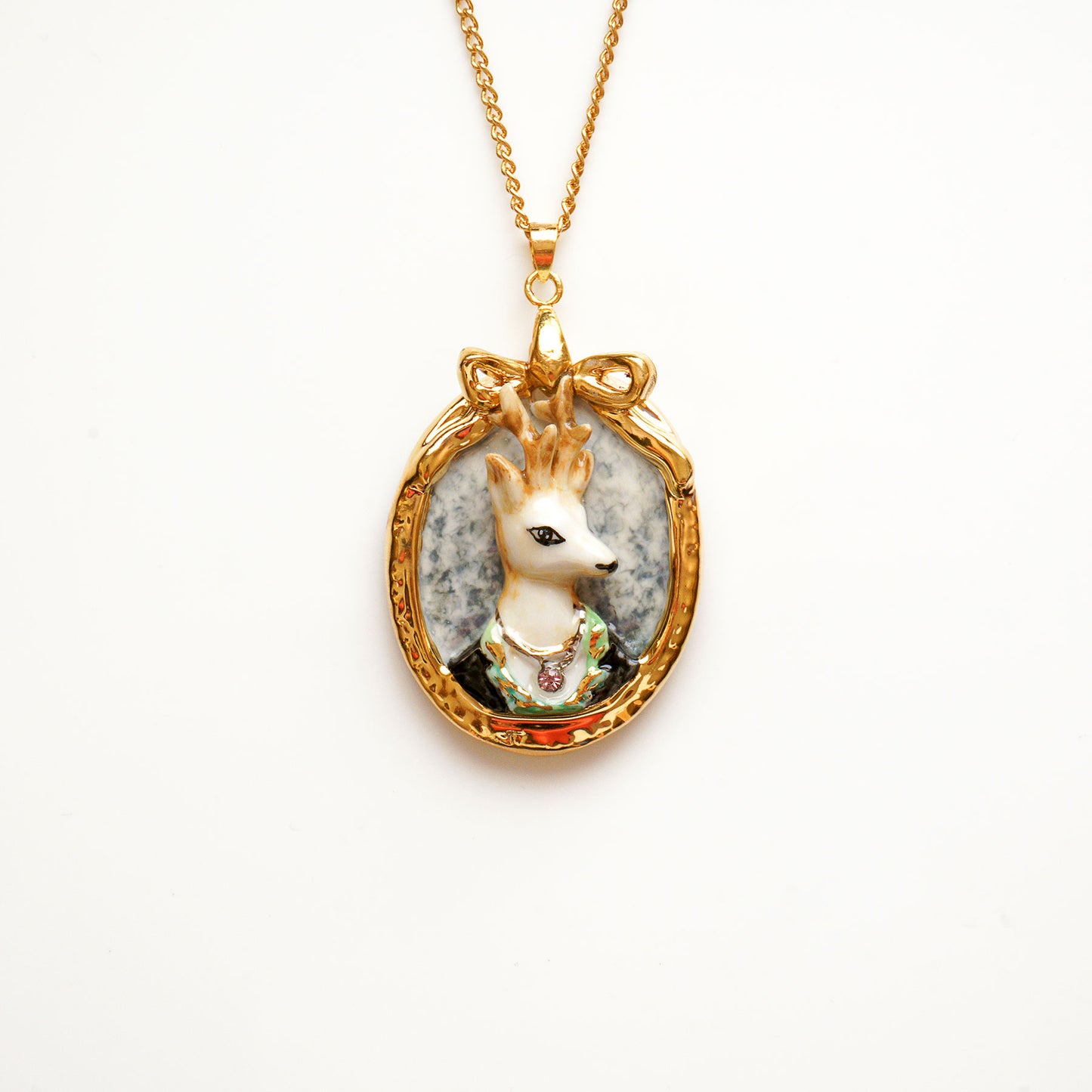 A charming stag pendant known as Prince Ambrose is famous in his handsome look. Designed and handmade from porcelain in a portrait design. Hand painted with 24ct gold, silver and colour. Embellished with Swarovski crystals for a luxurious touch. Come with 24'' gold plated necklace. This prince charming pendant will enhance a cool edge to your outfit.