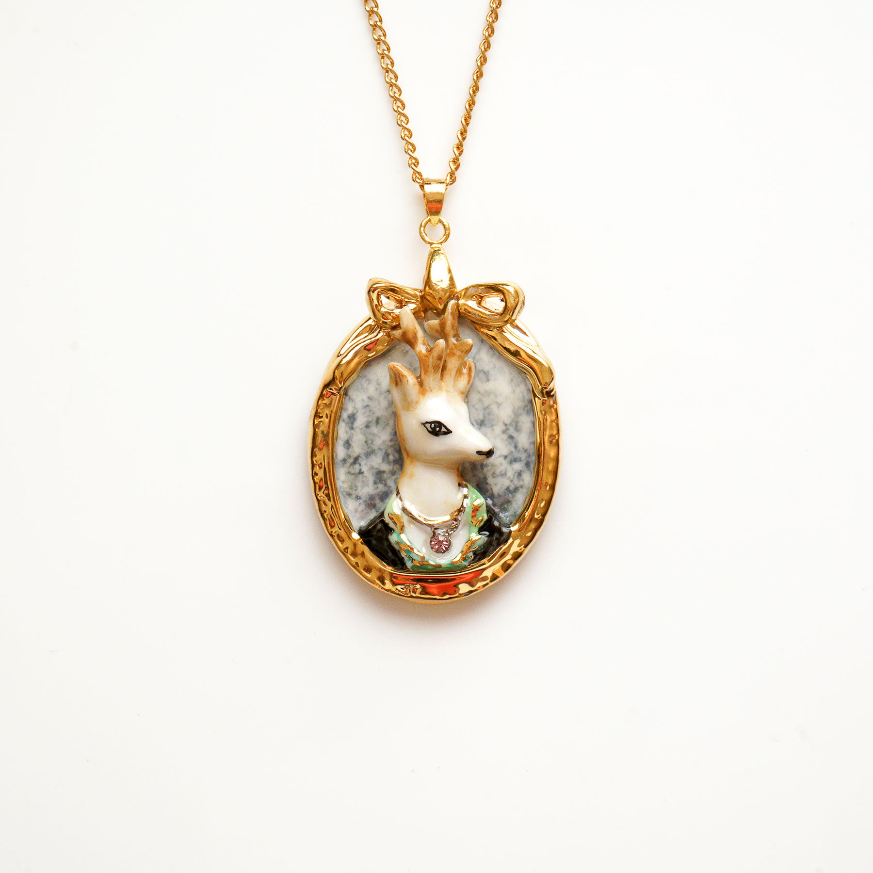 A charming stag pendant known as Prince Ambrose is famous in his handsome look. Designed and handmade from porcelain in a portrait design. Hand painted with 24ct gold, silver and colour. Embellished with Swarovski crystals for a luxurious touch. Come with 24'' gold plated necklace. This prince charming pendant will enhance a cool edge to your outfit.